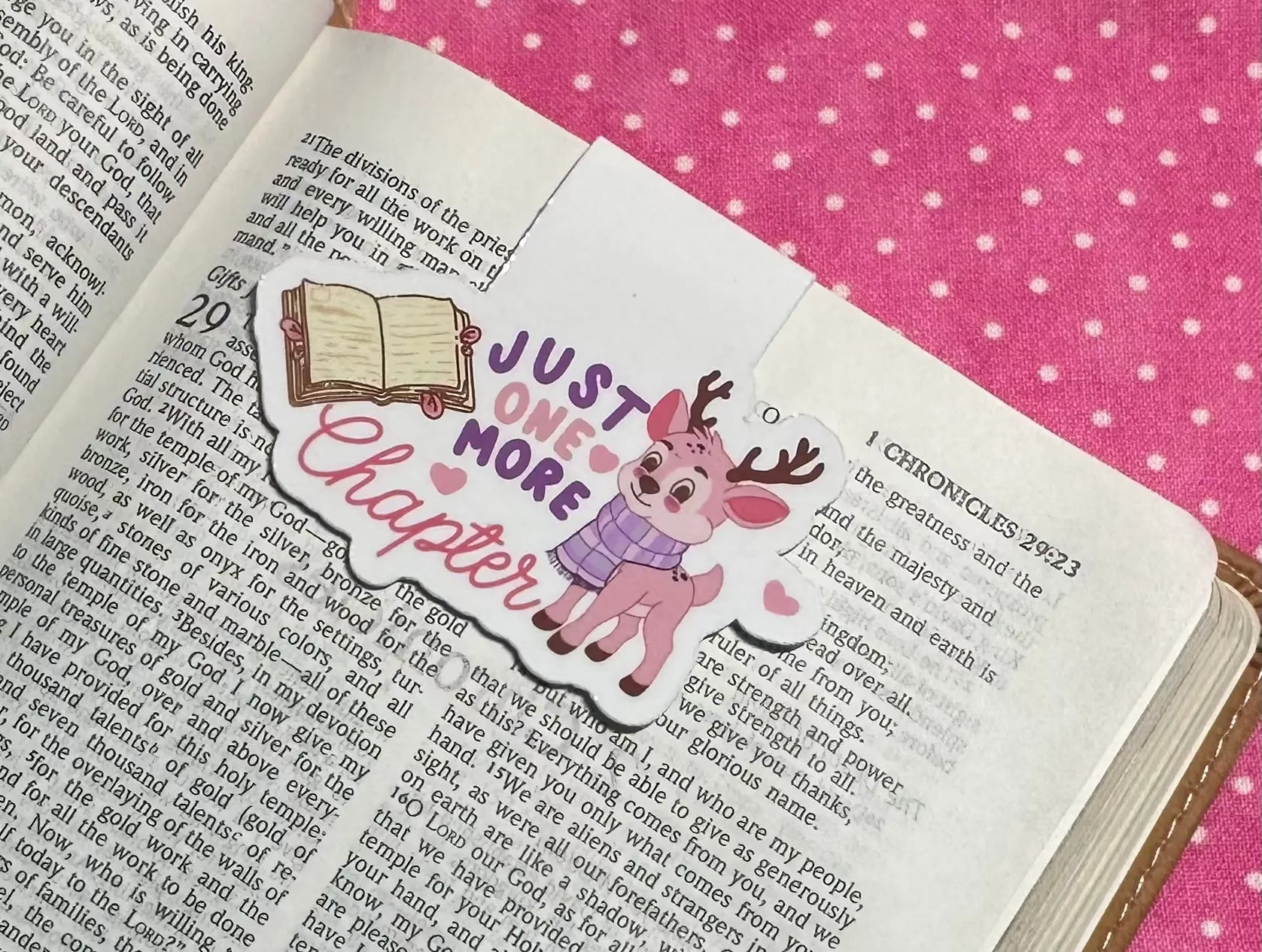 Open book with a decorative sticker of a deer and text on a pink polka dot fabric background