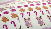 Sheet of Christmas-themed stickers featuring reindeer, gingerbread men, and candy canes on a white background.