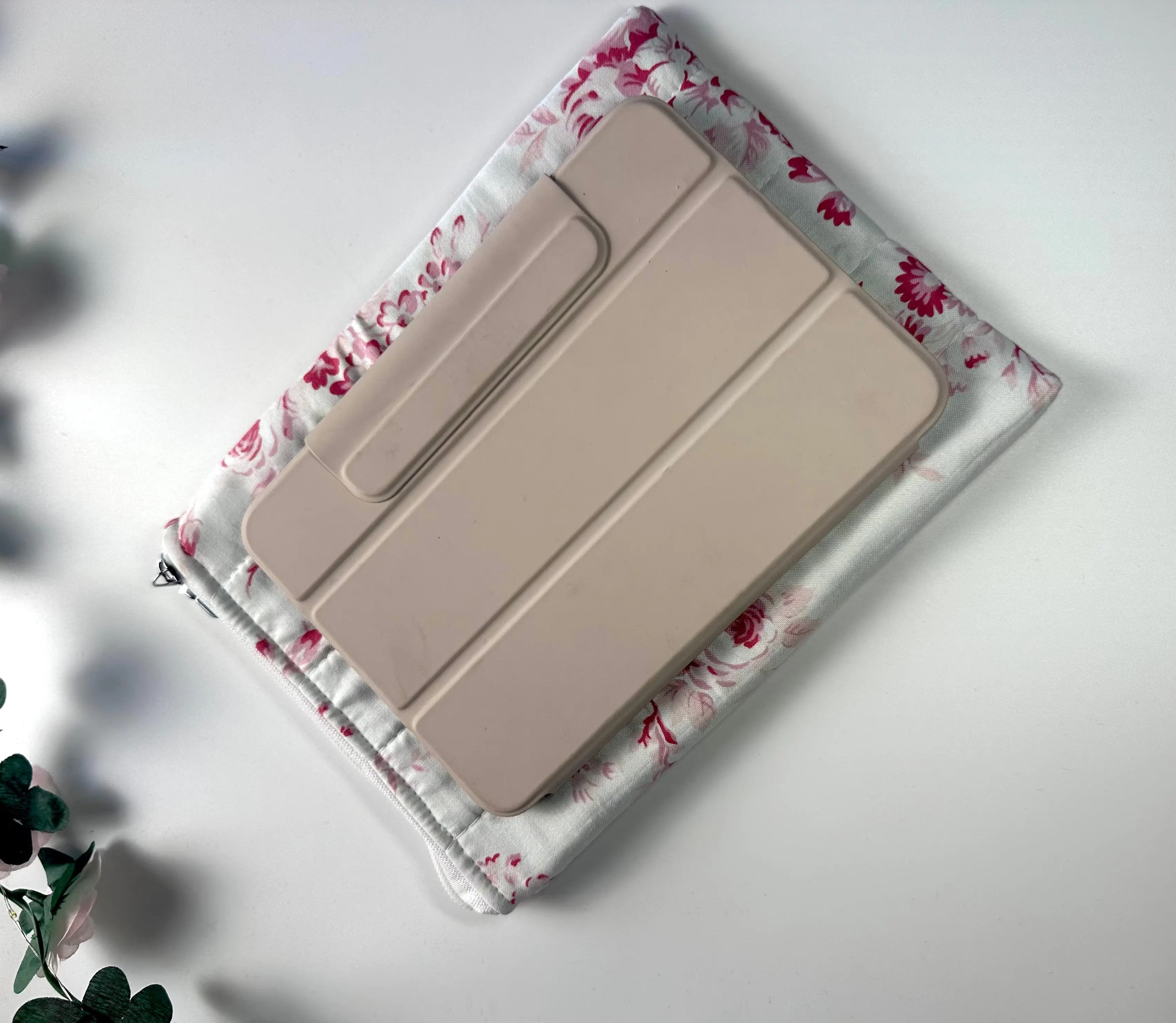 Beige tablet case on a floral fabric cover with a white background