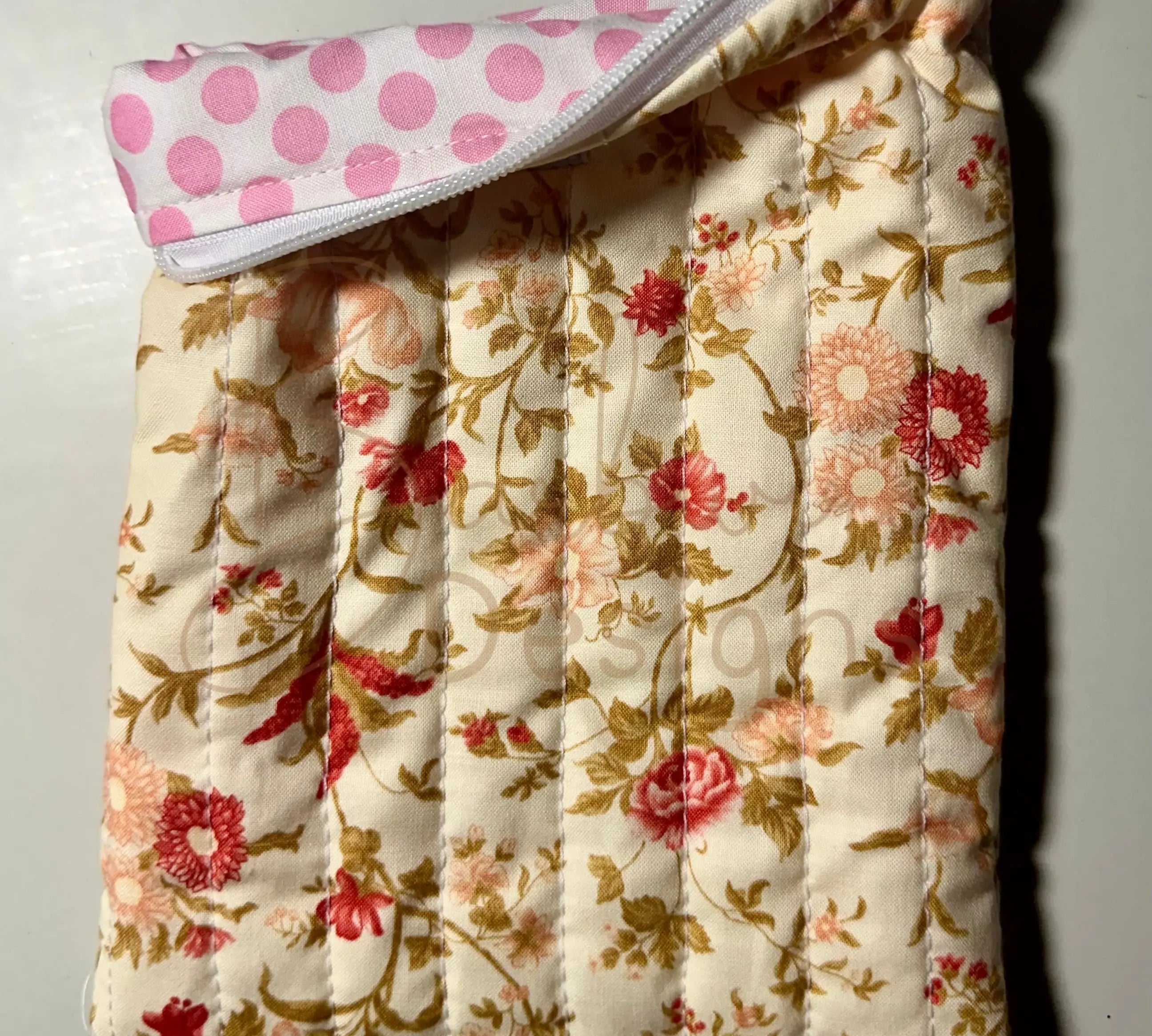 Floral-patterned quilted item with a pink polka dot cover on a light background