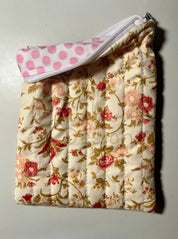 Floral-patterned quilted item with a pink polka dot cover on a light background