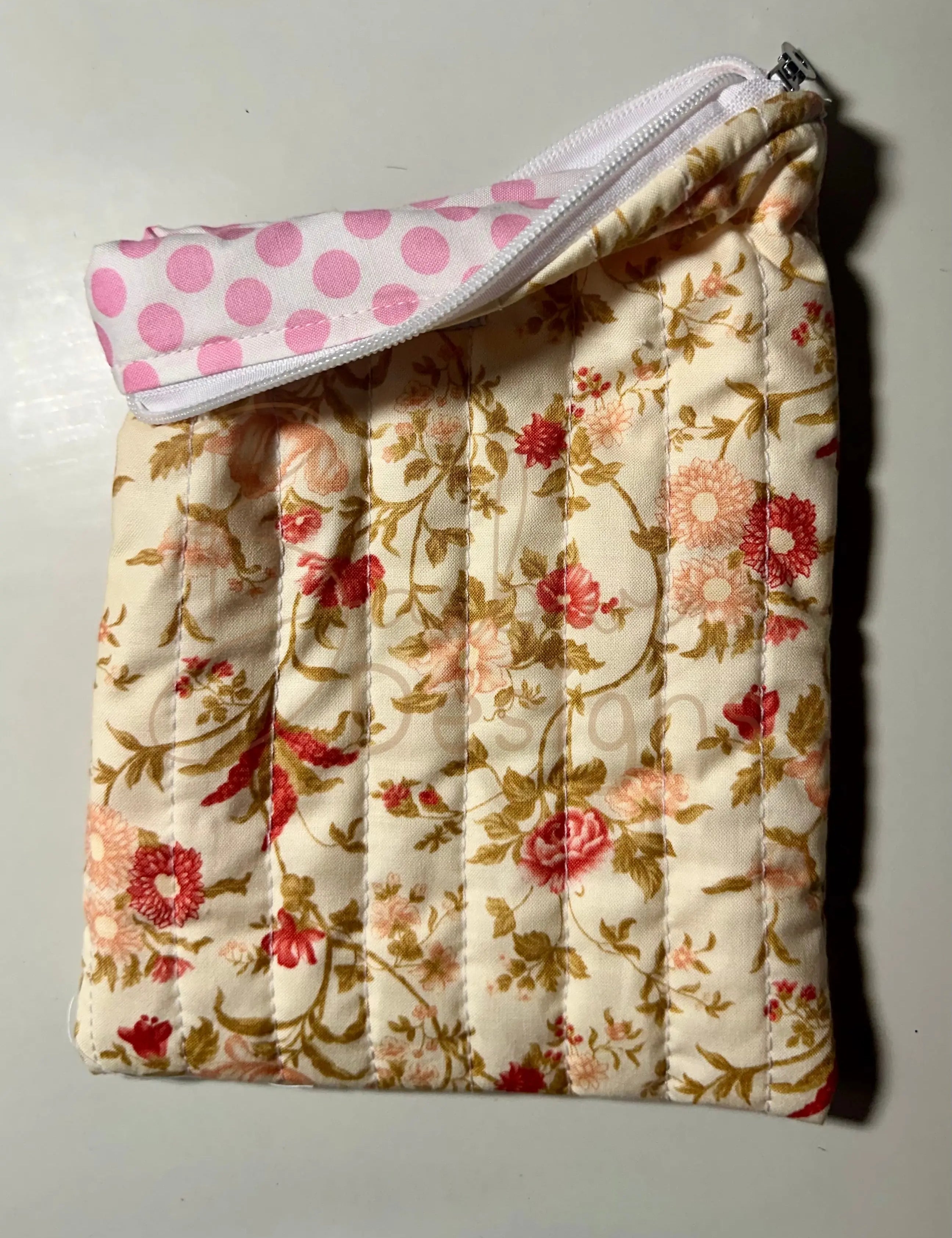 Floral-patterned quilted item with a pink polka dot cover on a light background