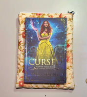 Book titled 'Cursed' by Mila Young on a floral-patterned surface