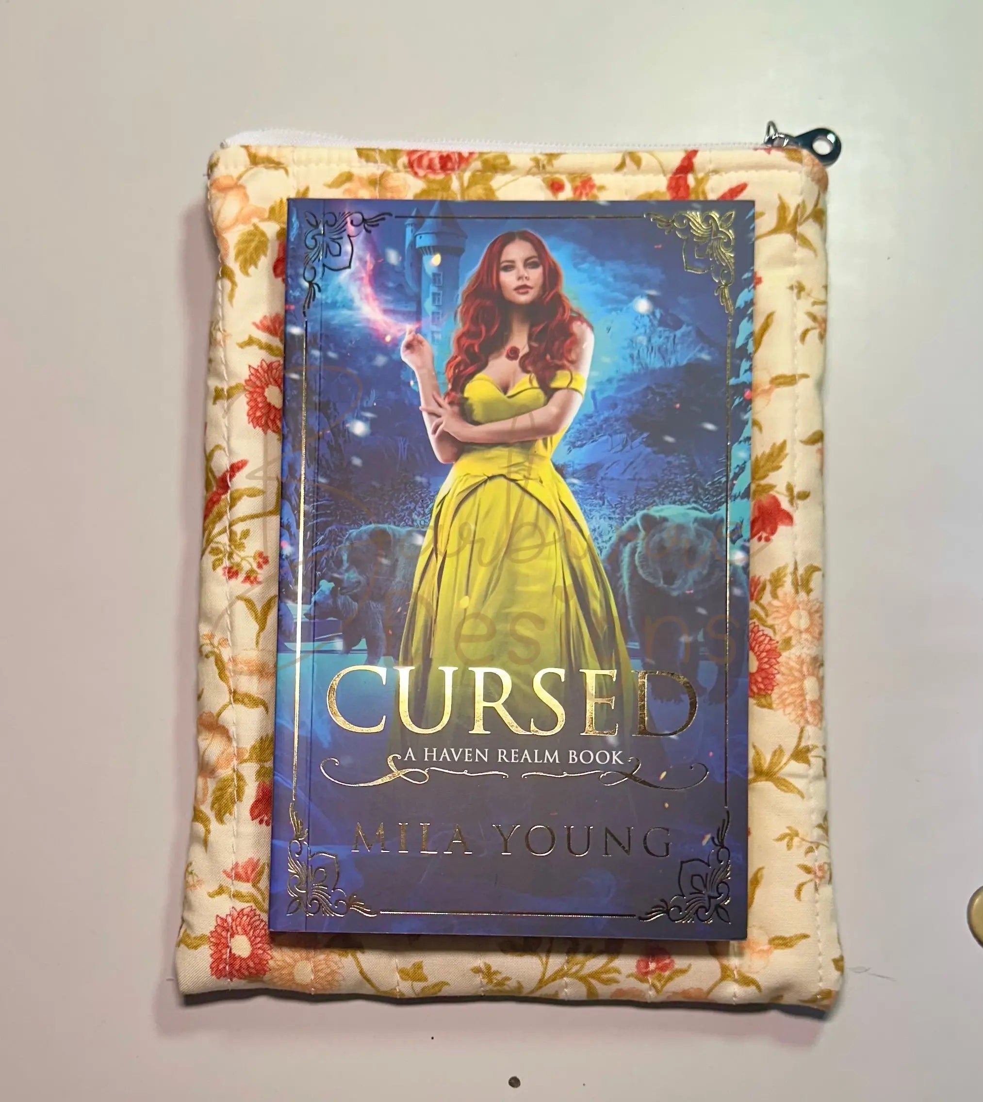 Book titled 'Cursed' by Mila Young on a floral-patterned surface
